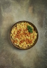 Risotto with shrimp, in a bowl, on a textured surface, with a side dish of fresh coriander,