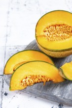 Freshly sliced melon slices, cantaloupe melon, on a wooden chopping board, close-up