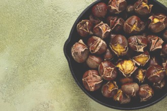 Roasted chestnuts, in an iron pan, wooden table, top view, no people, rustic style