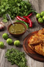 Baked tobacco chicken, served with tkemali sauce, on a wooden table, Georgian cuisine, rustic