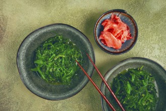 Chuka salad made from fresh seaweed, with sesame dressing, two bowls with chopsticks and pickled