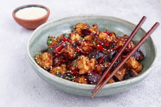 Fried eggplant, Chinese style, in sweet and sour sauce, with pepper and sesame seeds, in a green