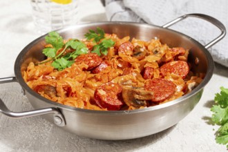 Polish dish bigos, in a stainless steel pan, stewed meat with cabbage, chorizo sausages, mushrooms,