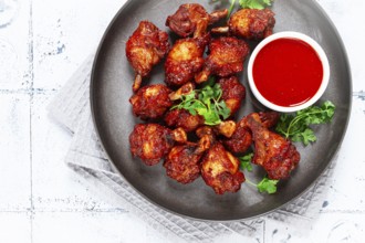 Crispy pieces of fried chicken, on a plate with sauce and herbs, in a modern kitchen environment,