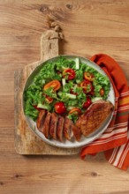 Delicious grilled duck breast served with fresh garden salad and cherry tomatoes at a rustic dining