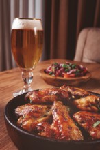 Delicious barbecue chicken wings, with French fries, salad and a refreshing drink, at a cozy table,