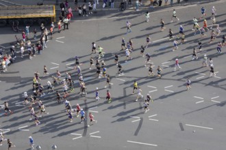 Runners with long shadows on the big star seen from the Victory Column at the 51st BMW Berlin