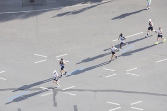 Runners with long shadows on the big star seen from the Victory Column at the 51st BMW Berlin