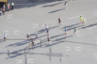 Runners with long shadows on the big star seen from the Victory Column at the 51st BMW Berlin