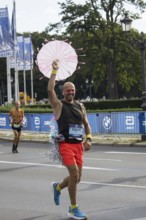 A runner with an umbrella on the Großer Stern at the 51st BMW Berlin Marathon 2025 on 21 September