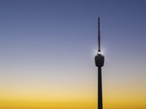 Illuminated television tower in front of a harmonious yellow-blue morning sky, Stuttgart,