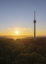 The television tower rises above the forest at sunrise, sky in warm colours, Stuttgart,