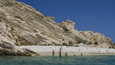 Group of people swimming in clear water in front of rocky beach landscape, White Cliffs, White