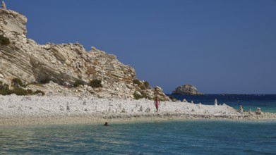 Rocks and a pebble beach meet turquoise waters under a clear sky, White Cliffs, White Beach, Makri