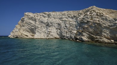 An imposing cliff rises above the blue sea under a bright sky, White Cliffs, White Beach, Makri