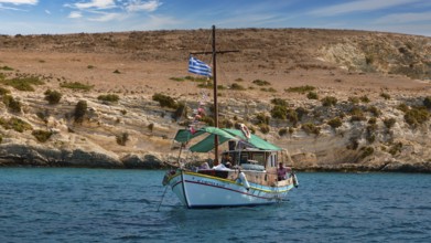 A boat with a Greek flag sails along rocky shores, the sea is blue and calm, White Cliffs, White