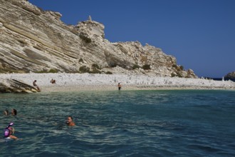 People swimming in calm turquoise waters off a rocky coast, White Cliffs, White Beach, Makri