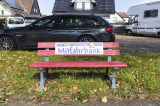 Red bench at the roadside, sign with inscription Mitfahrbank, Mitfahrerbank, symbol photo, carpool,