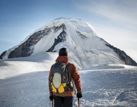 Lone climber equipped with winter gear trekking through pristine snow towards a towering mountain