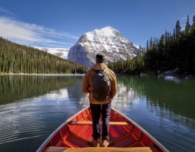 A serene moment of solitude depicted as an individual rows a boat across a tranquil mountain lake