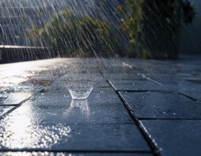Close-up image showing rainfall splashing on wet ground during daylight in the background, AI