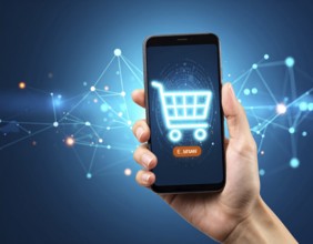 Hand holding smartphone glowing shopping cart icon poster symbolizing online shopping, e-commerce,