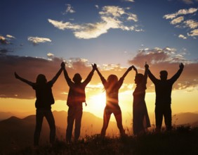 A group of friends celebrating together, leaping with joy against a breathtaking sunset. Their