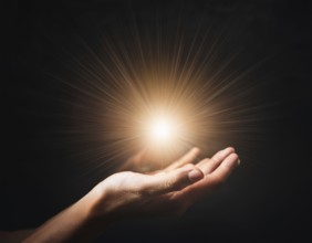 Image of open hand embracing a radiant light source, embodying concepts of hope, spirituality, and