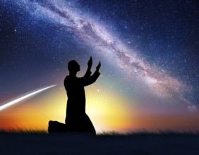 A man kneels in peaceful reflection under the vibrant Milky Way galaxy at sunset in an open natural