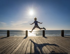Silhouette of an individual joyfully leaping during a dramatic sunset, symbolizing freedom. An