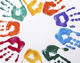 Brightly colored handprints in various hues arranged artistically on a textured white surface,