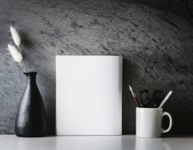 A clean and modern office workspace featuring a pen holder, notebook, and ceramic vase against a