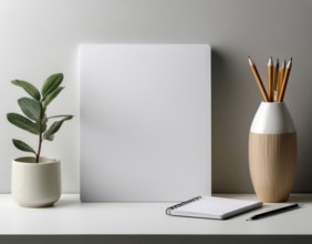 A clean, organized workspace featuring decorative objects, a white blank canvas, greenery, and