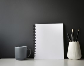 A clean, organized workspace featuring decorative objects, a white blank canvas, greenery, and