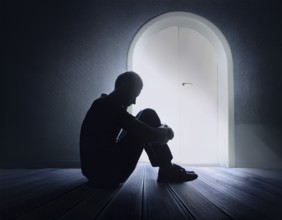 A silhouette of a person seated on the floor, conveying feelings of sadness and solitude against a