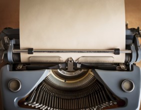View from above of a retro typewriter equipped with a blank paper sheet, representing creativity,