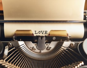 View from above of a retro typewriter equipped with 'love' word paper sheet, representing