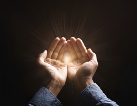 Image of open hands embracing a radiant light source, embodying concepts of hope, spirituality, and