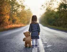 A young child stands alone holding a teddy bear in an urban outdoor setting, symbolizing innocence