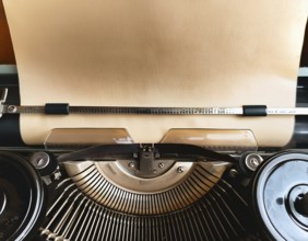 View from above of a retro typewriter equipped with a blank paper sheet, representing creativity,