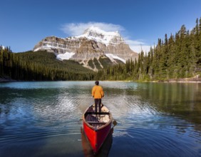 A serene moment of solitude depicted as an individual rows a boat across a tranquil mountain lake