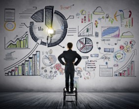 A professional individual stands before a wall filled with business sketches, including colorful