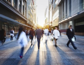 A dynamic scene featuring blurred people walking in a city street surrounded by skyscrapers and