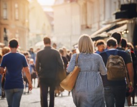 A vibrant urban street captures a diverse crowd enjoying a stroll under the warm sunlight, with