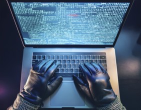 Cybersecurity threat depicted by gloved hands operating a computer, commands displayed on the