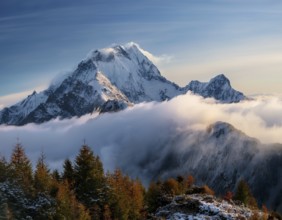 A stunning view of a snowy mountain peak rising above the clouds, with a blue sky background.