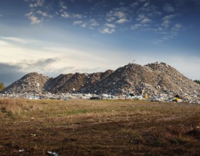 A scenic evening view of a large landfill site with piles of collected waste surrounded by open