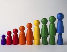 Wooden figurines painted in vibrant rainbow colors, arranged in a neat line on a white surface.