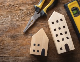 A detailed layout of miniature wooden houses accompanied by various tools on a textured wooden
