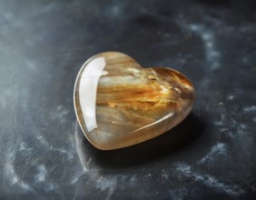 A heart-shaped gemstone with vivid colors placed on a textured surface, capturing an elegant and